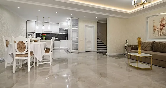An open-concept living and dining area featuring seamless, reflective light grey marble flooring that ties the spaces together.