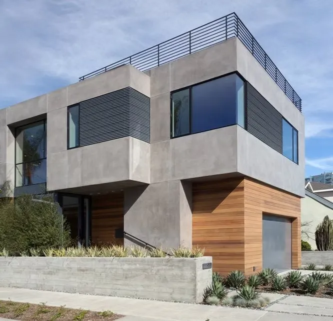 A multi-story cubist home combining smooth grey concrete panel facades with warm horizontal wood cladding and a roof terrace.