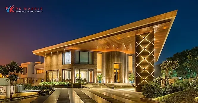 A striking evening view of the modern, architectural showroom facade of R K Marble with warm accent lighting.
