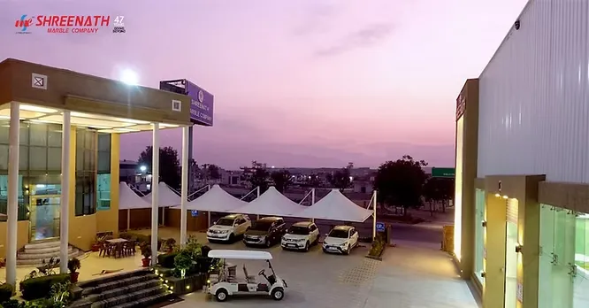 A wide shot of the Shreenath Marble Company showroom premises and courtyard facility during a purple twilight.