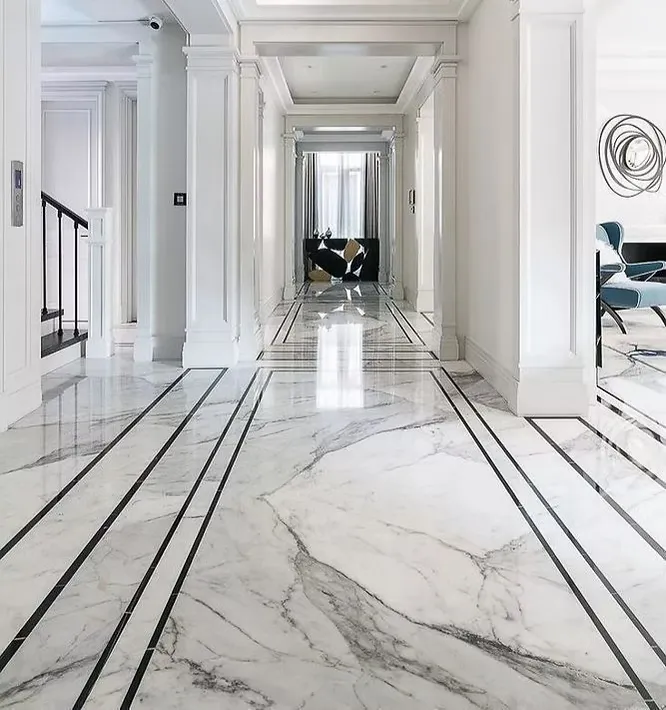 An elegant, polished white marble hallway floor accented with bold, linear black border inlays stretching down a grand corridor.