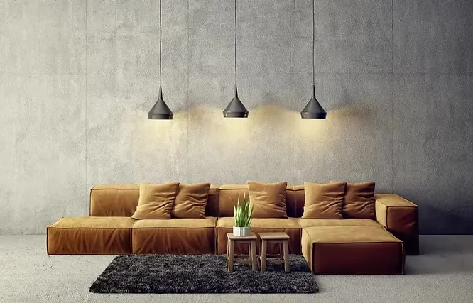 Three black modern pendant lights hanging over a long brown couch against a textured grey concrete wall.