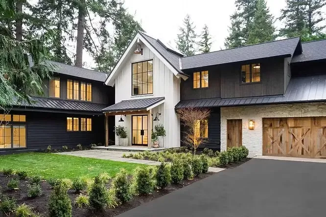 High-contrast modern farmhouse design showcasing striking matte black siding alongside a stark white central entryway gable.