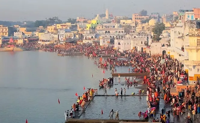 Dense crowds of devotees gather along the sprawling, sacred ghats of Pushkar Lake during a holy festival in Rajasthan.