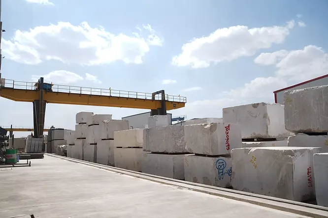 Massive raw blocks of white marble sit organized in a sprawling open-air industrial yard at the Kishangarh Marble Market.
