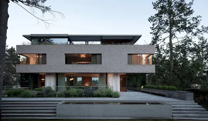 Sleek two-story modern house displaying clean geometries, sharp structural rectangles, and clear glass balconies.