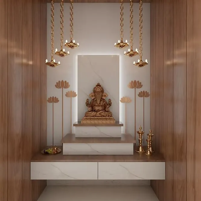 Modern pooja alcove with a white marble mandir platform, warm wood paneling, a golden Ganesha idol, and hanging brass lamps.