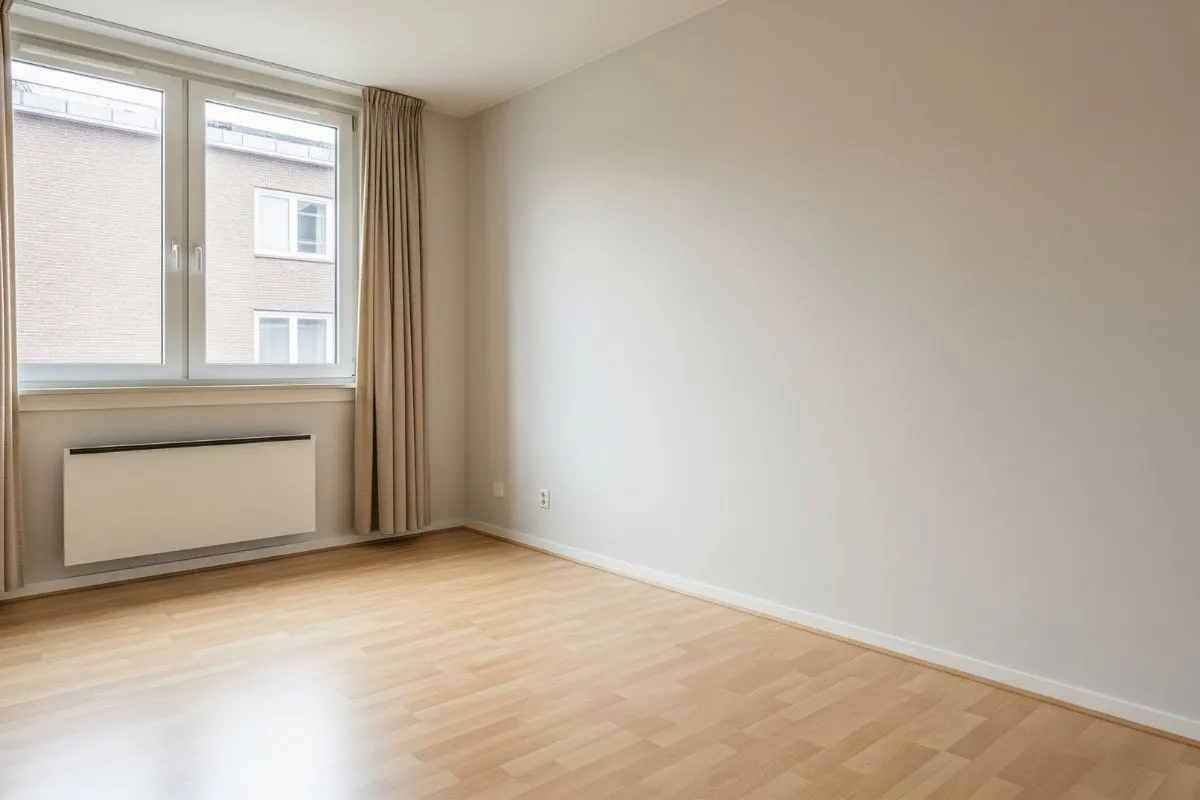 A blank, empty room with light hardwood floors and large windows, illustrating the first step of planning for home interiors.