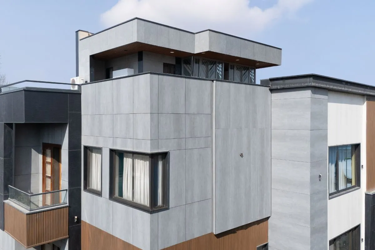 A multi-story modern home featuring a striking exterior with large, grey porcelain slabs and wooden accents, showcasing a clean and contemporary home front design.