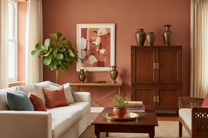 A warm space with rich terracotta walls, dark wood furniture, and colorful velvet pillows. These earthy Living Room Paint Ideas create a fresh, sophisticated, and inviting look.