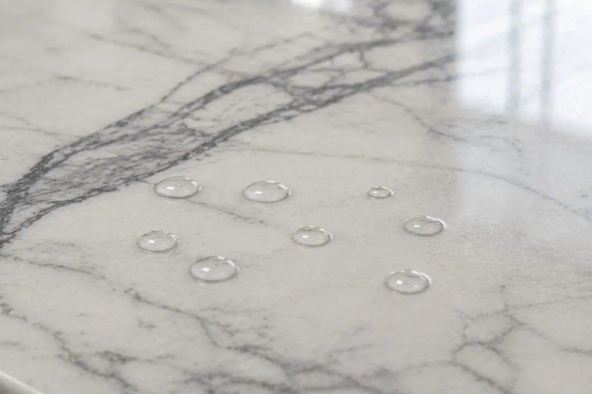 Clear water drops sitting on top of a smooth, white Kitchen Marble Slab to test it.