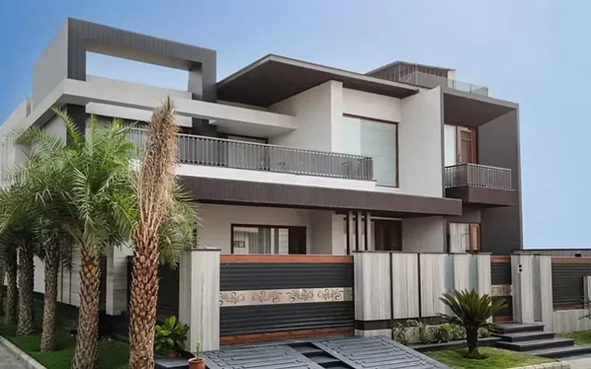 A luxurious multi-level villa featuring large-format porcelain slab walls, sleek grey framing, and tall palm trees lining the front walkway.