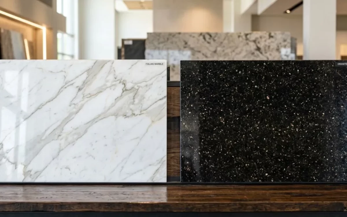 Marble and Granite Difference: A white veined marble slab next to a dark granite slab for kitchen countertop choice.
