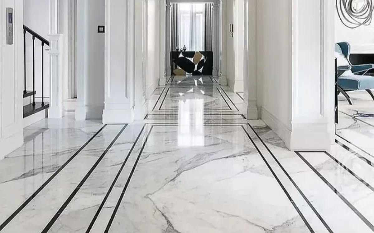 An elegant, polished white marble hallway floor accented with bold, linear black border inlays stretching down a grand corridor.