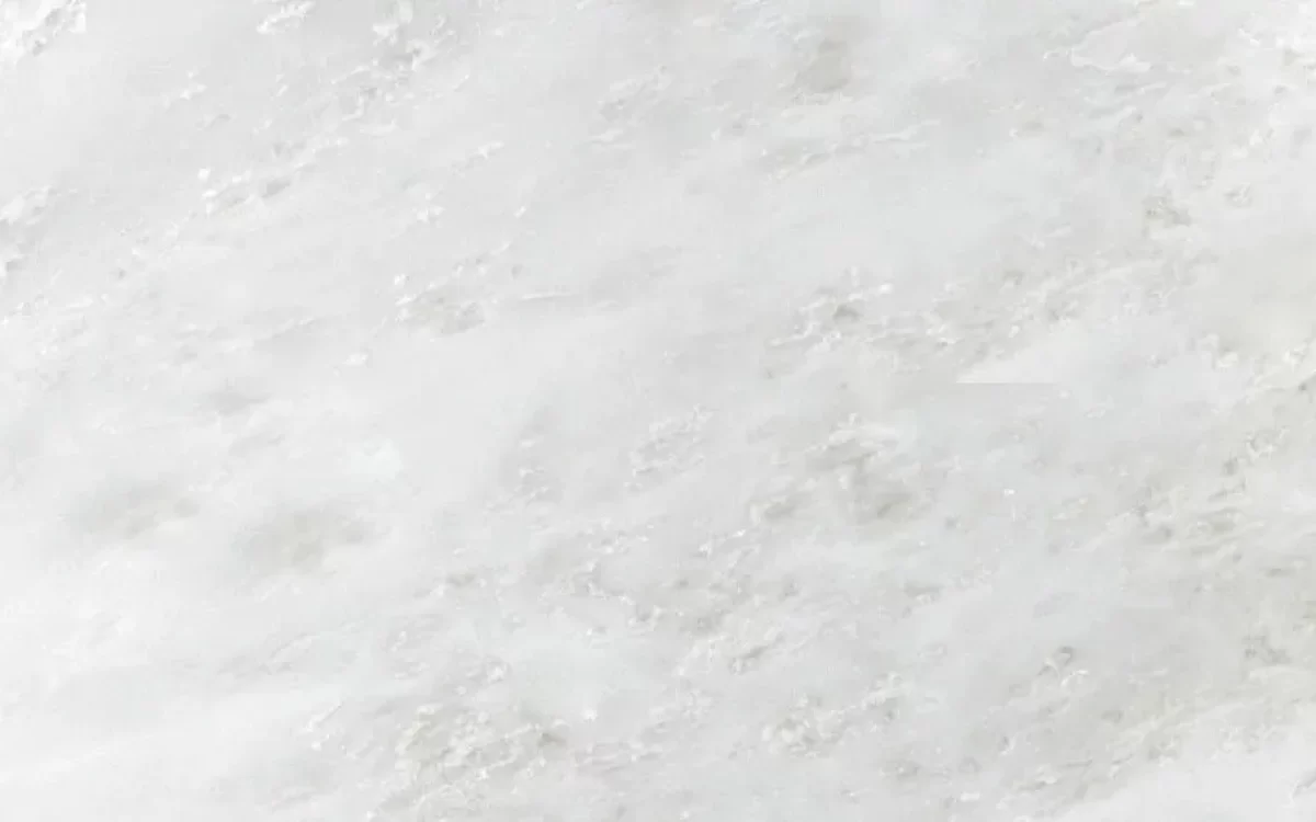 A close-up view of a premium white Namibian marble slab featuring soft, delicate light gray and cream veins.